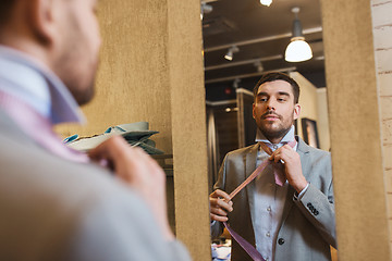 Image showing man tying tie on at mirror in clothing store