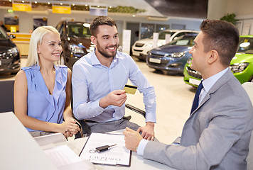 Image showing happy couple with car dealer in auto show or salon