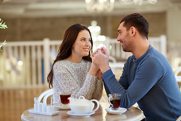 Image showing happy couple with tea holding hands at restaurant