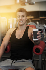 Image showing smiling young man with smartphone in gym