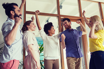 Image showing happy creative team celebrating victory in office