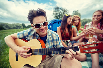 Image showing happy man with friends playing guitar at camping