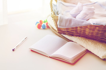 Image showing close up of baby clothes for newborn and notebook