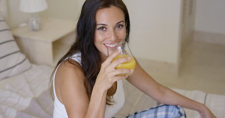 Image showing Smiling healthy young woman drinking orange juice