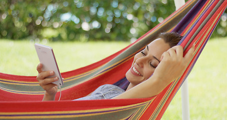 Image showing Happy young woman listening to music in a hammock