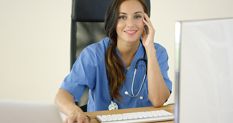 Image showing Young female physician places one hand on her face