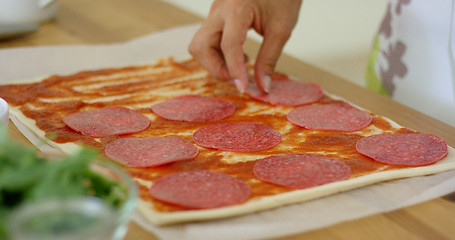 Image showing Woman making a homemade salami and mushroom pizza