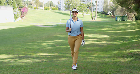 Image showing Smiling friendly woman golfer walking on a course