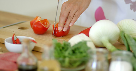 Image showing Housewife chopping a fresh red bell pepper