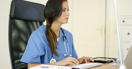 Image showing Young female doctor sitting typing in her office