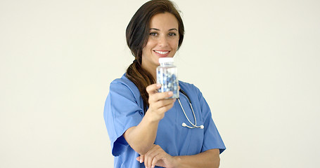 Image showing Young brown haired doctor in scrubs holds bottle