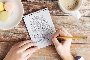 Image showing close up of hands drawing scheme to notebook