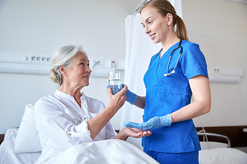 Image showing nurse giving medicine to senior woman at hospital