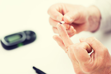 Image showing senior woman with glucometer checking blood sugar