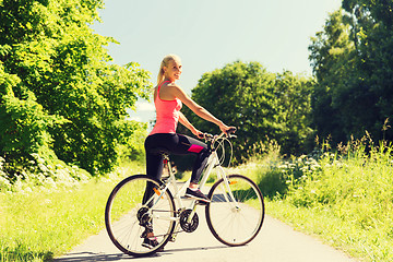 Image showing happy young woman riding bicycle outdoors