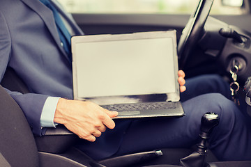 Image showing close up of young man with laptop driving car
