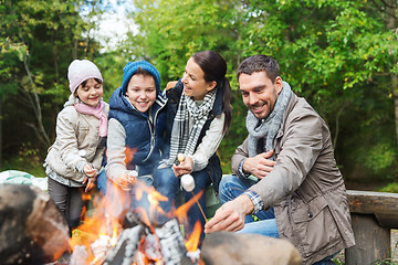 Image showing happy family roasting marshmallow over campfire