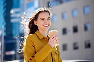 Image showing happy young woman drinking coffee on city street