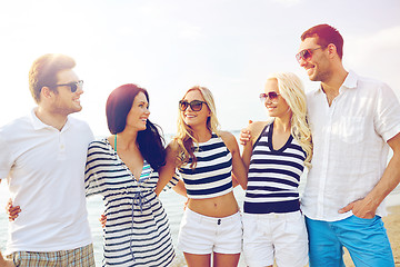 Image showing smiling friends in sunglasses talking on beach