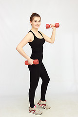 Image showing Portrait of young beautiful woman making physical exercises with dumbbells