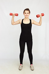 Image showing Portrait of young beautiful woman making physical exercises with dumbbells