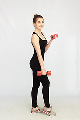 Image showing Portrait of young beautiful woman making physical exercises with dumbbells