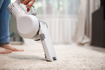 Image showing Woman cleaning carpet wireless rechargeable vacuum cleaner