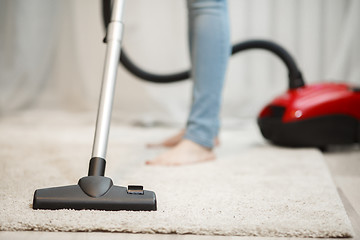 Image showing Woman cleaning carpet with vacuum cleaner