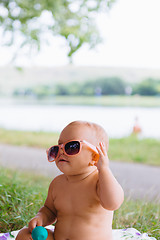 Image showing Baby in big sunglasses on a river