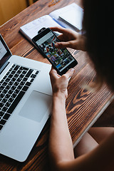 Image showing Woman working on computer and looking at the phone