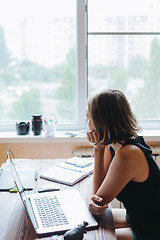 Image showing Woman sitting at computer and looking out the window