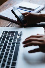 Image showing Woman working on computer and looking at the phone