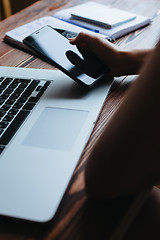 Image showing Woman working on computer and looking at the phone