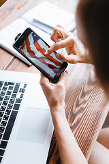 Image showing Woman working on computer and looking at the phone