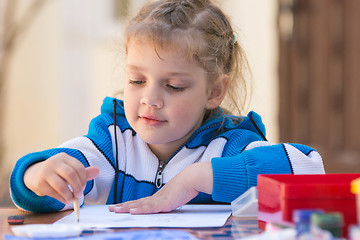 Image showing Pretty girls sitting at a table in the courtyard of the house and draws pencil