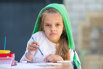 Image showing Thoughtful and enthusiastic girl draws a painting at the table and looked at the frame