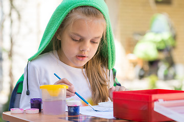 Image showing Girl draws paints in the yard in the spring sunny day