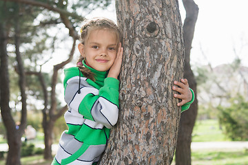 Image showing Joyful seven-year old girl sitting on a tree trunk in the early spring