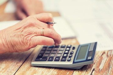 Image showing close up of senior woman counting with calculator