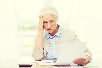 Image showing senior woman with papers and calculator at home