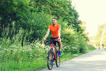 Image showing happy young man riding bicycle outdoors