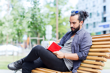 Image showing man with notebook or diary writing on city street