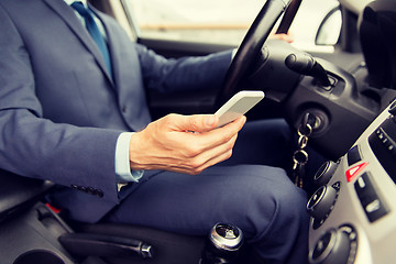 Image showing close up of man with smartphone driving car