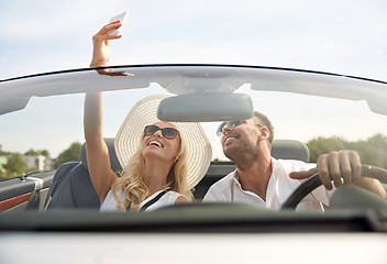 Image showing happy couple in car taking selfie with smartphone