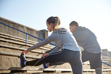 Image showing couple stretching leg on stands of stadium