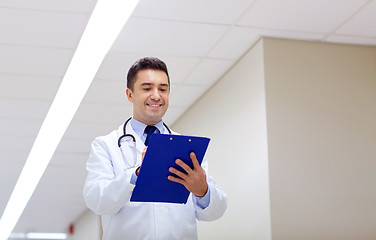 Image showing smiling doctor with clipboard at hospital corridor