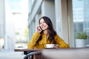 Image showing happy woman calling on smartphone at city cafe