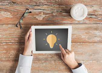 Image showing close up of hands with lighting bulb on tablet pc