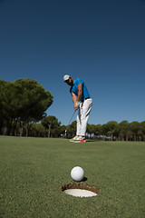 Image showing golf player hitting shot, ball on edge of hole