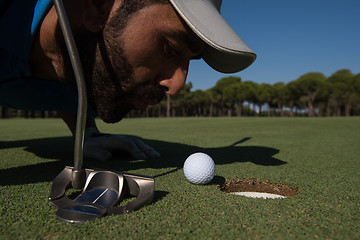 Image showing golf player blowing ball in hole